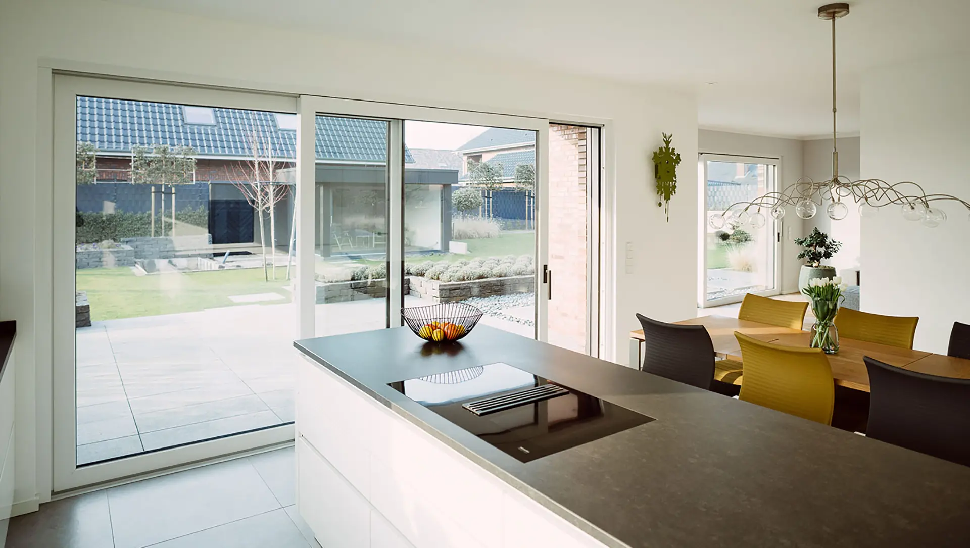 Kunststoff-Schiebetüren in einer hellen, modernen Küche, über die man zur Terrasse gelangen kann.