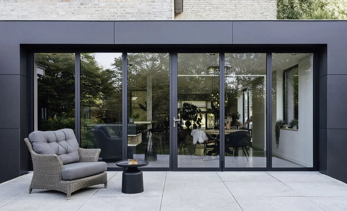 Man kann durch eine moderne und elegante Glas-Faltwand mit dunklem Rahmen in eine modern eingerichtete Wohnung sehen.