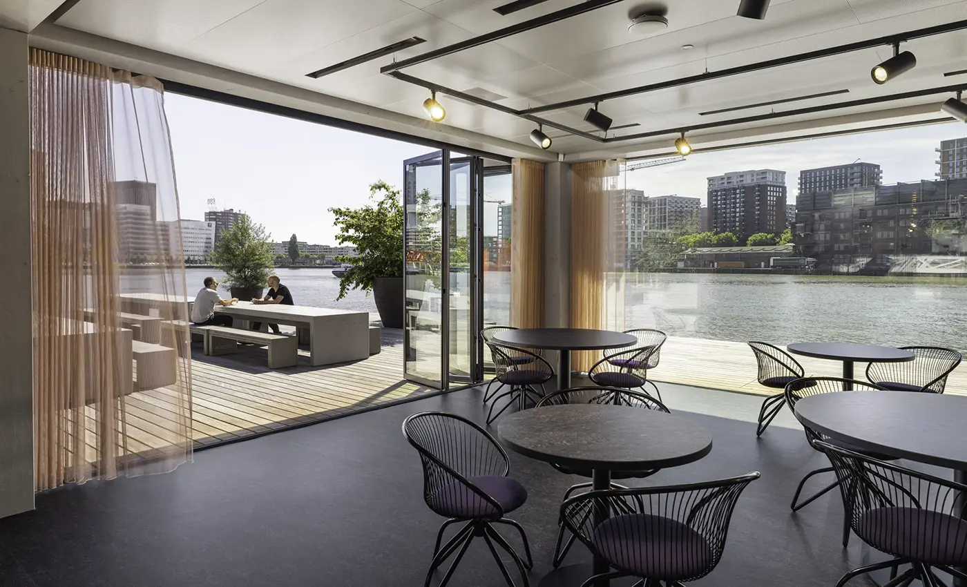 Modernes Lokal mit geöffneter Glas-Faltwand-Front auf eine Terrasse am Wasser.