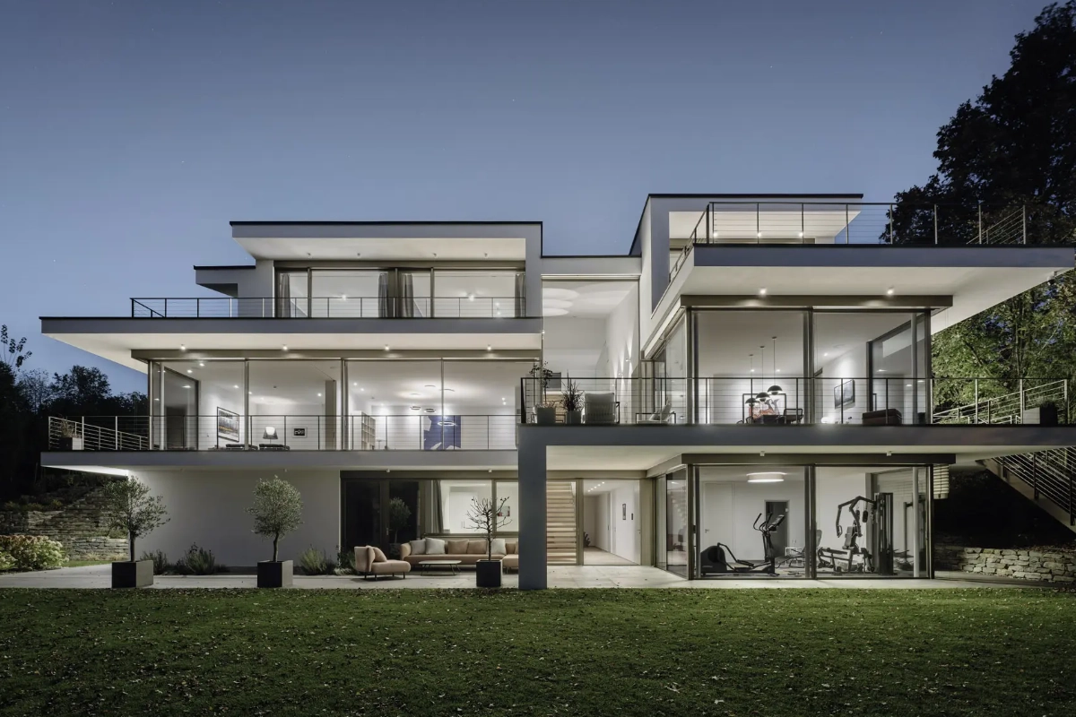 Stilvolle Terrasse mit Außenjalousien Modernes Gebäude mit vielen Glasfronten am Abend.